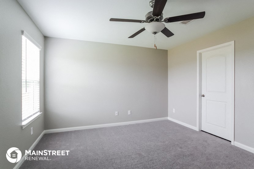 an empty room with a ceiling fan and a white door