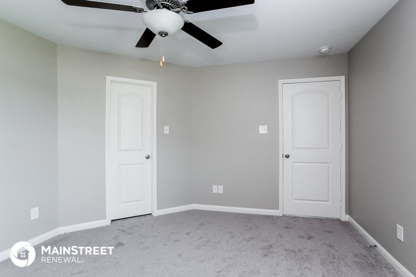 the interior of a room with two doors and a ceiling fan