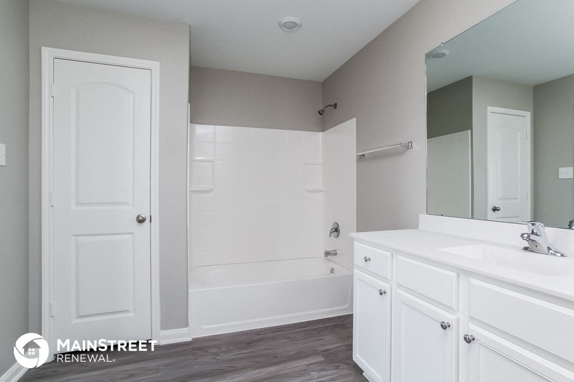 a bathroom with white cabinets and a tub and a sink