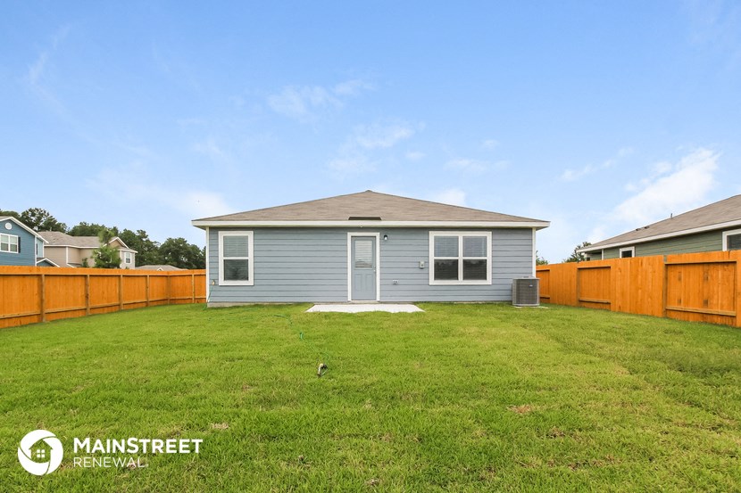 a backyard with a blue house and a wooden fence