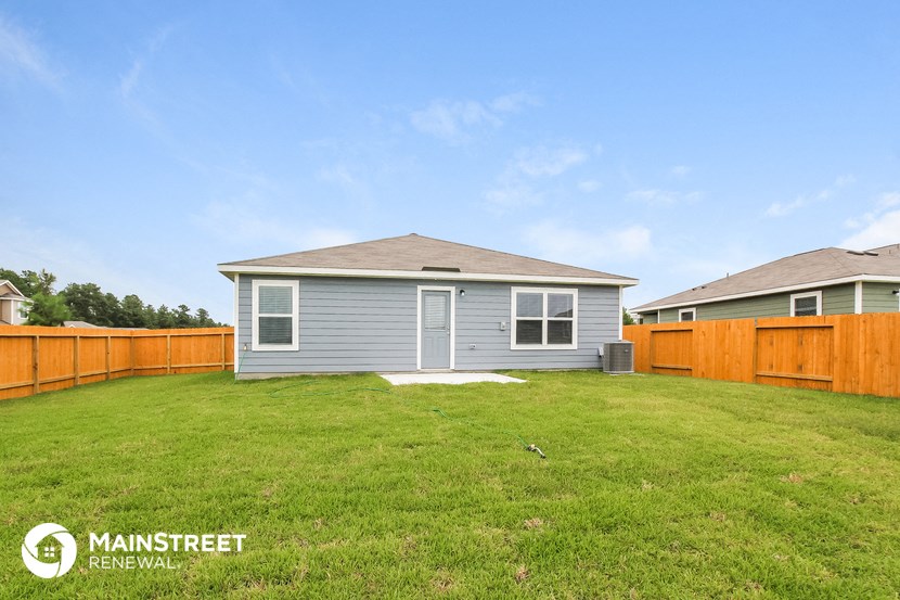 a backyard with a blue house and a wooden fence