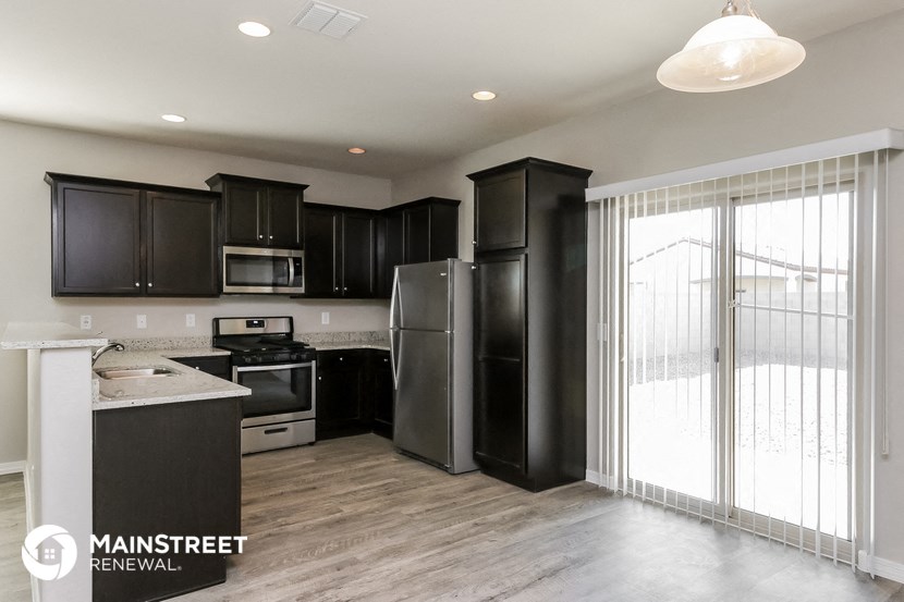 a kitchen with black cabinets and stainless steel appliances and a sliding glass door