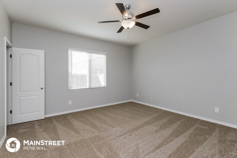 the spacious living room with ceiling fan and carpeting