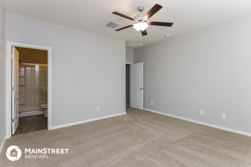 the spacious living room with ceiling fan and carpeting