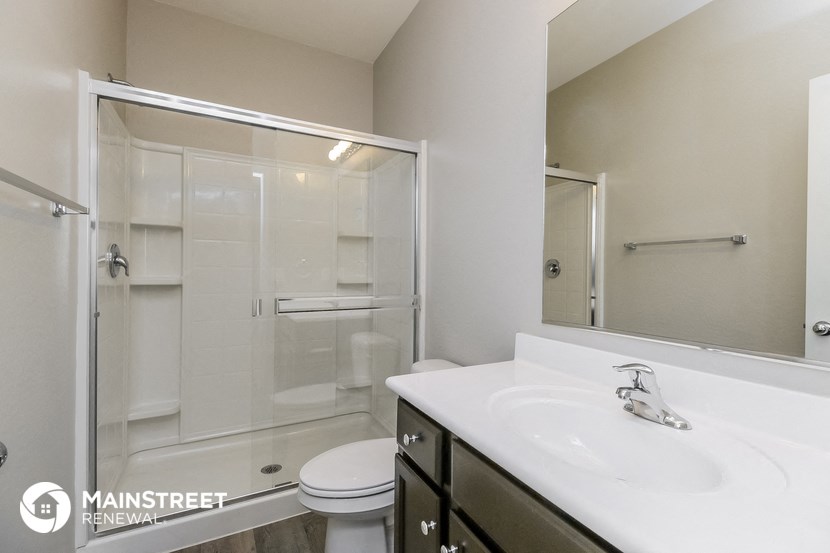 a bathroom with a shower sink and mirror and a toilet