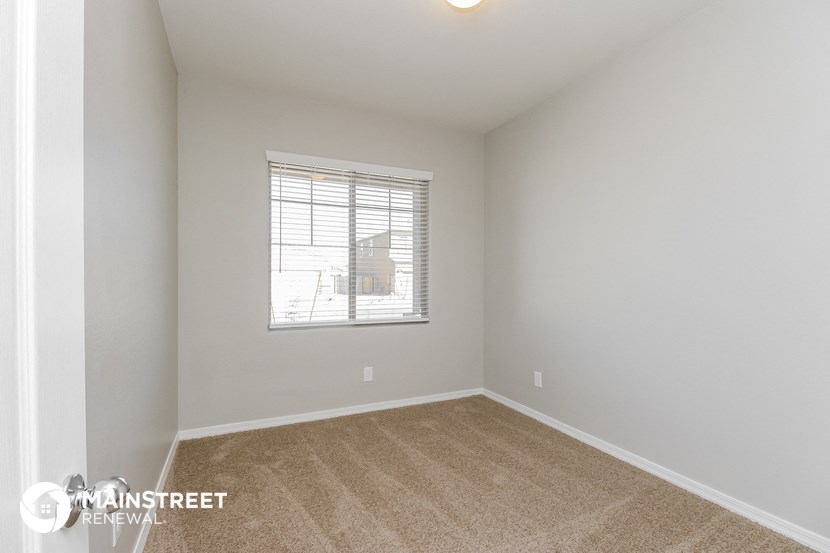 the spacious living room with a large window and carpeting