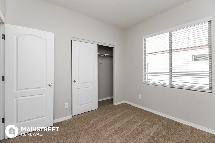 a bedroom with white doors and a closet and a window