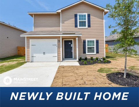 a tan house with a white garage door newly built home