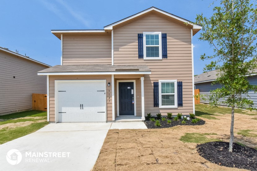 a tan house with a white garage door and a sidewalk in front of it