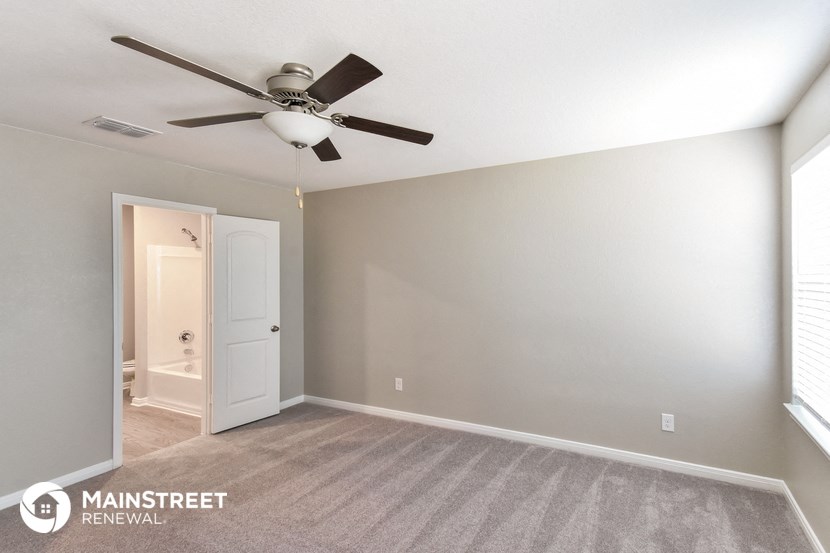 an empty room with a ceiling fan and a door to a bathroom