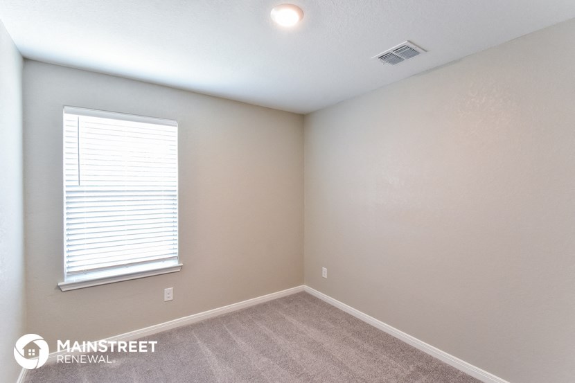 the upstairs bedroom has a carpeted floor and a large window