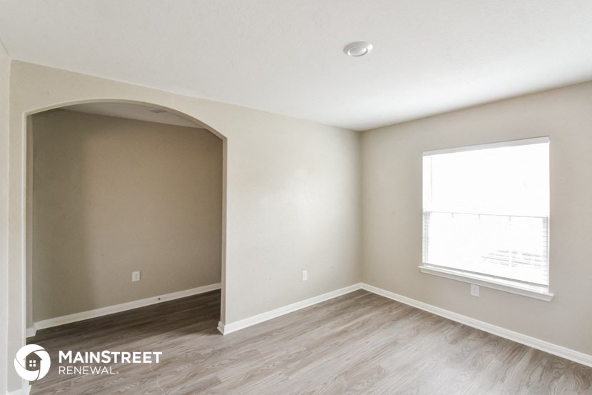 the interior of an empty room with wood flooring and a window