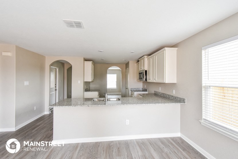 a spacious kitchen with white cabinets and a granite counter top