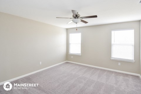 the spacious living room with carpet and ceiling fan