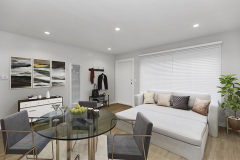 A modern living room with a glass table and grey chairs.