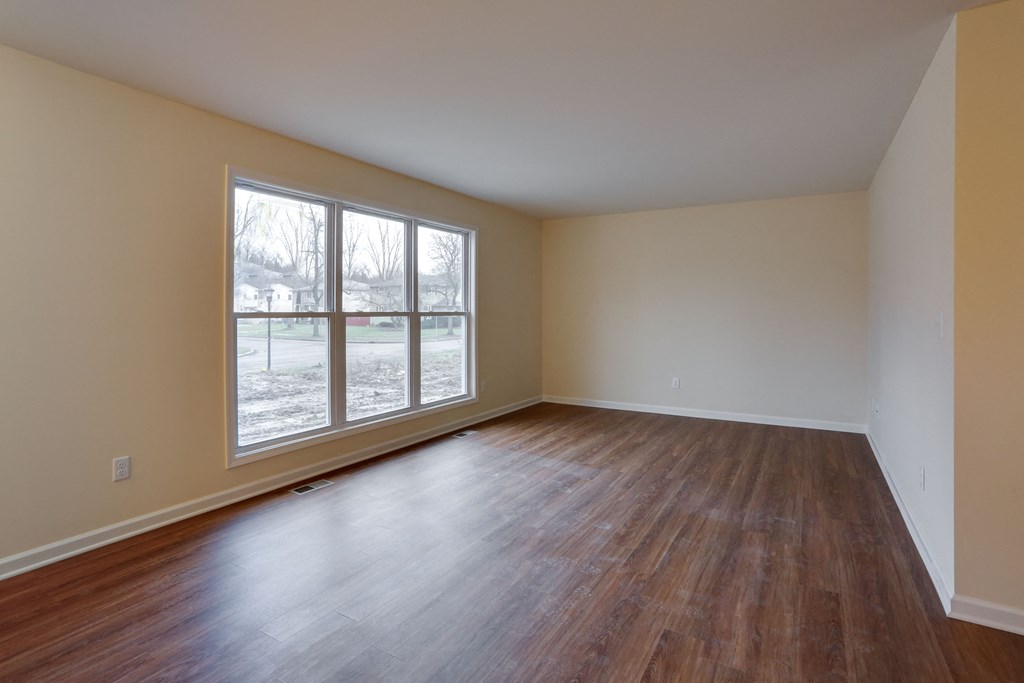 an empty living room with wood floors and a large window