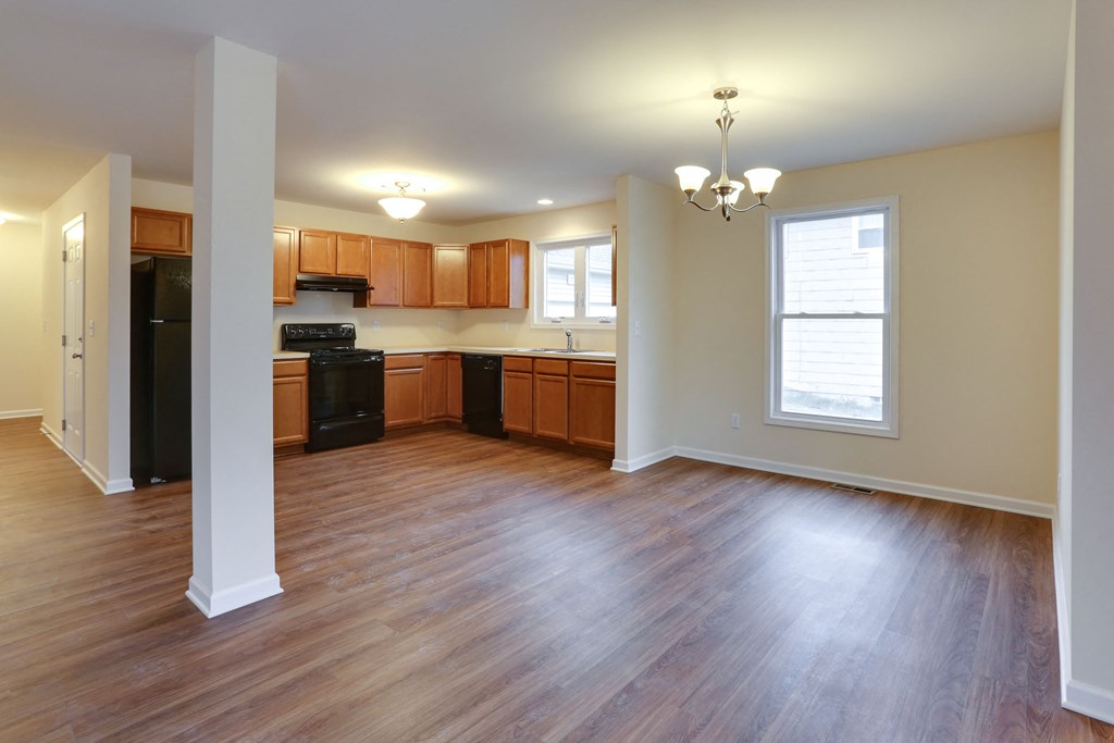 an empty living room and kitchen with wood flooring