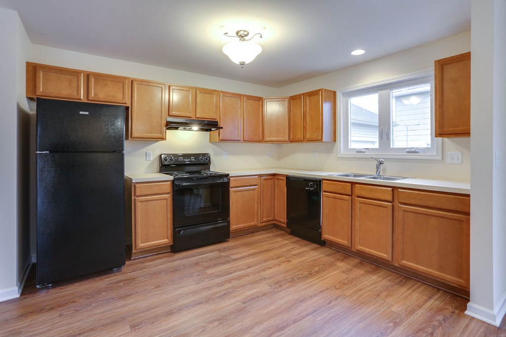 an empty kitchen with wood flooring and black appliances