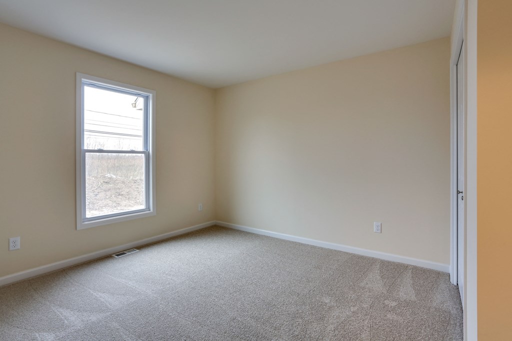 an empty living room with a window and carpet