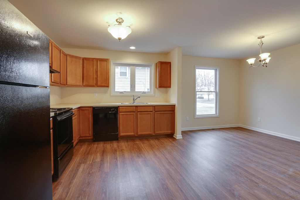 an empty kitchen with wood flooring and black appliances