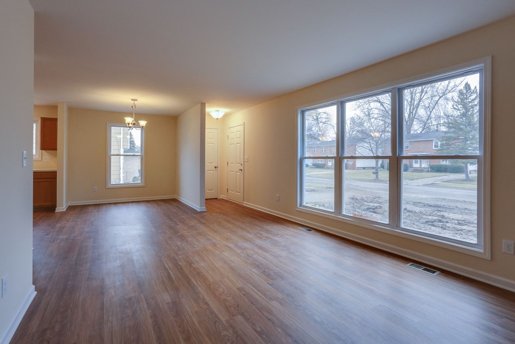 an empty living room with large windows and wood floors