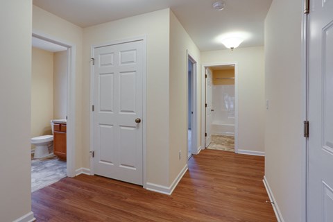 a bedroom with a white door and a hallway to a bathroom