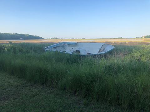 an abandoned boat in the middle of a field