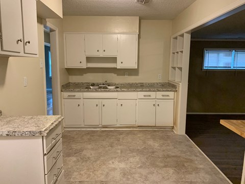 A kitchen with white cabinets and a marble countertop.