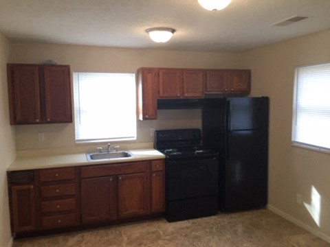 A kitchen with black appliances and wooden cabinets.