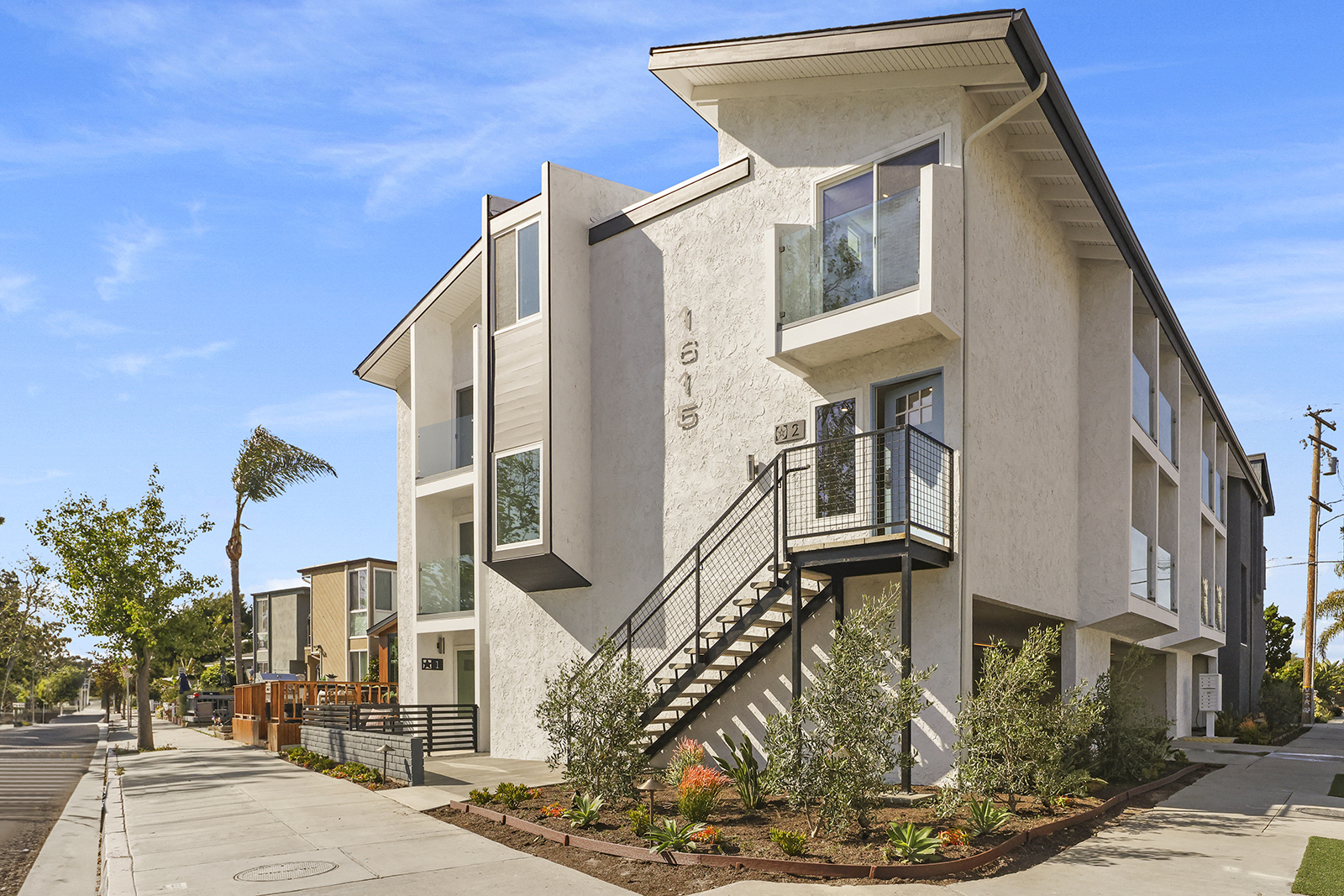 a row of town homes with stairs and balconies on a sidewalk