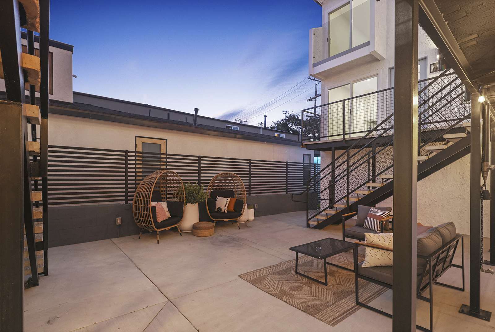 a patio with chairs and a table and a staircase