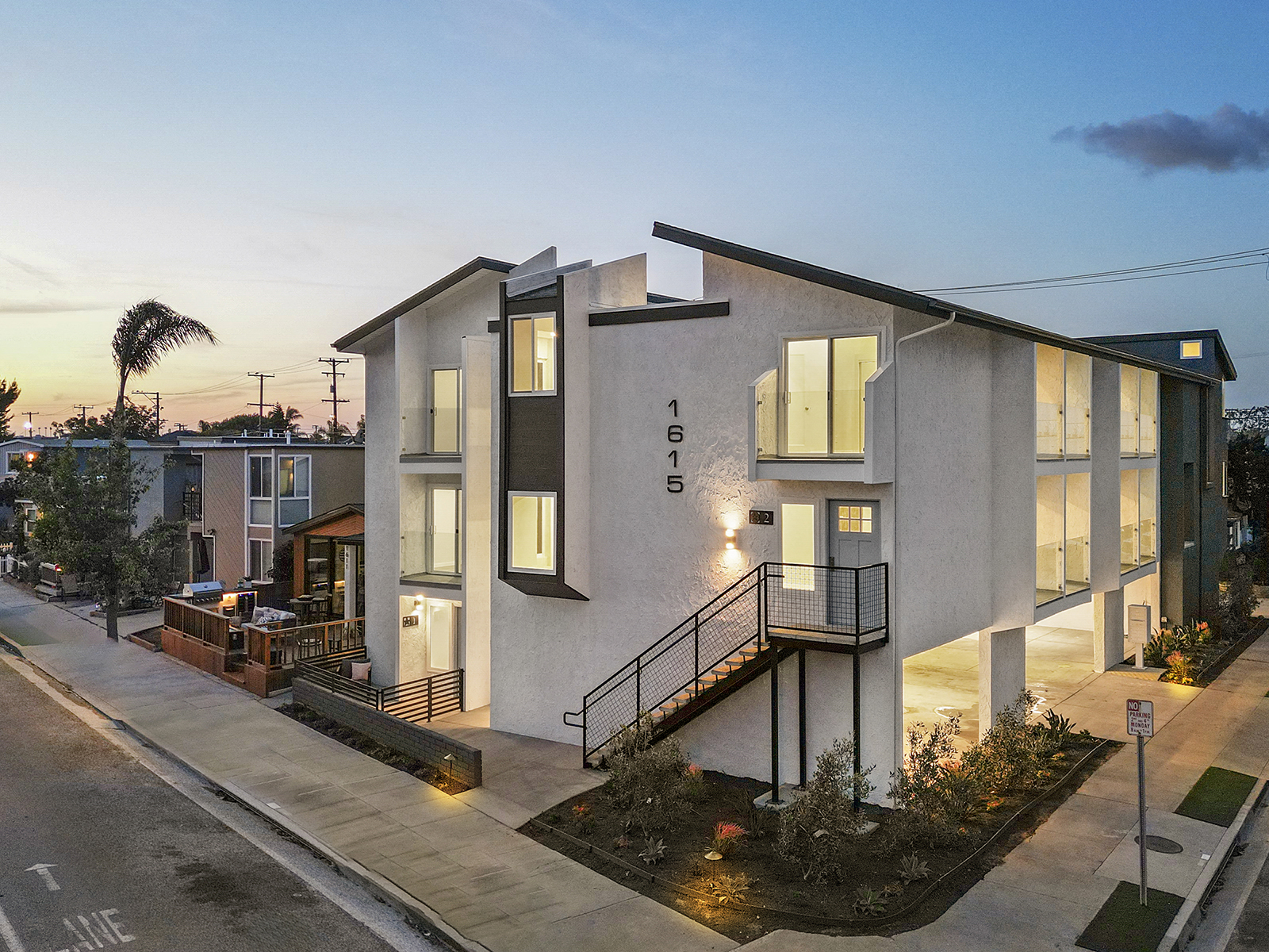 a condo building with stairs and a street at dusk