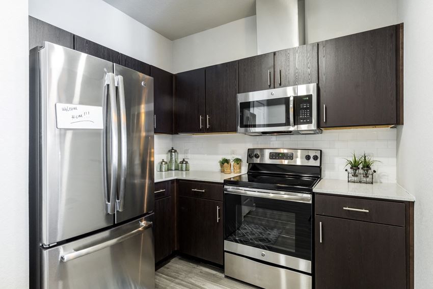 Kitchen with dark cabiets, stainless steel appliances, quartz countertops, and subway tile backsplash - Photo Gallery 1