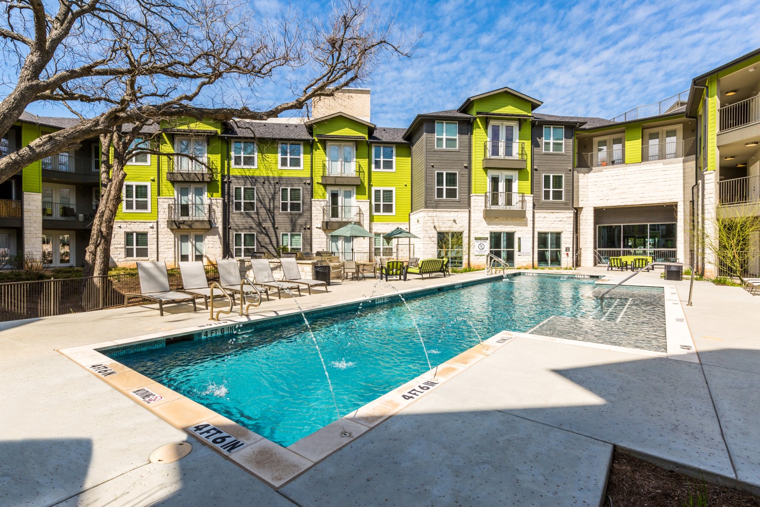 Pool with poolside lounge seating and umbrella shaded tables