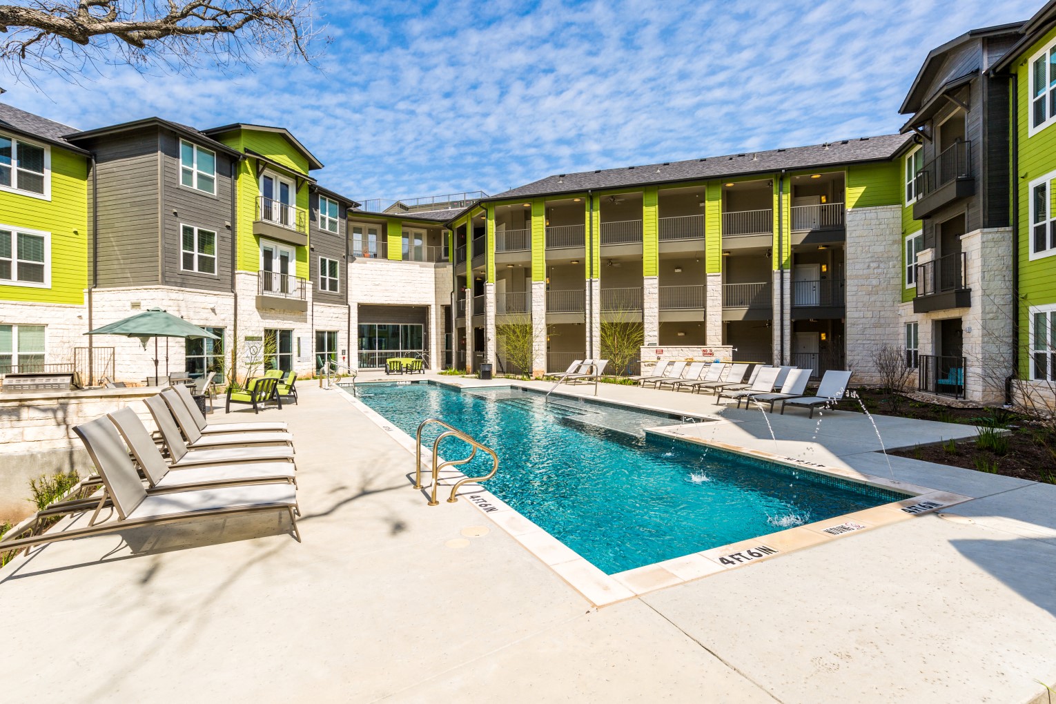 Pool with poolside lounge seating and umbrella shaded tables