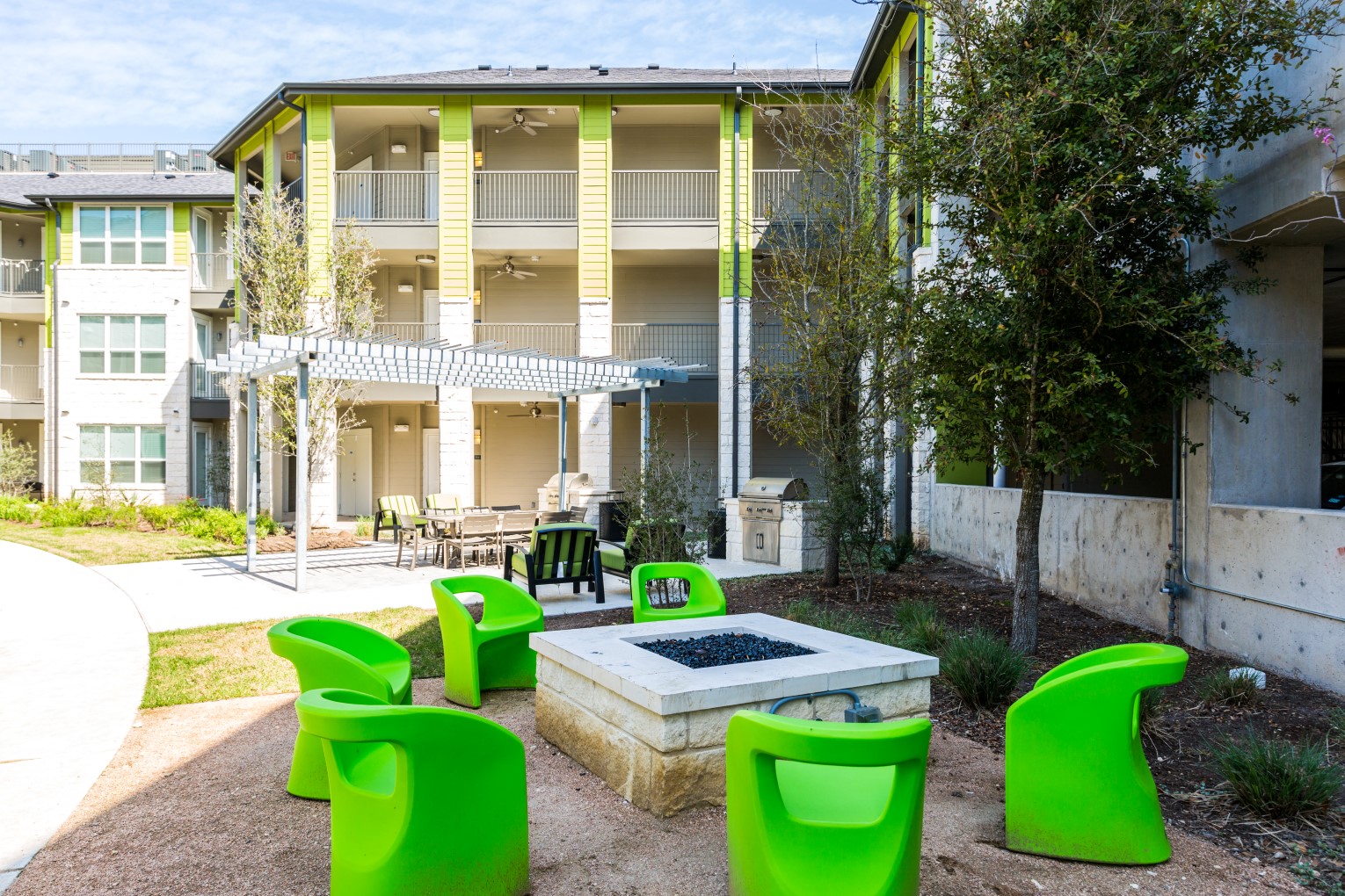 Outdoor firepit with fireside seating next to outdoor gazebo surrounded by landscape