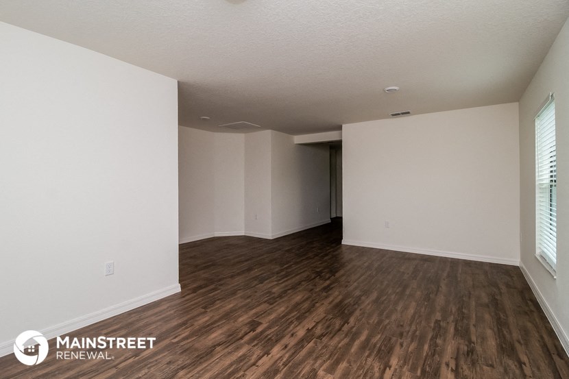 an empty living room with wood flooring and white walls