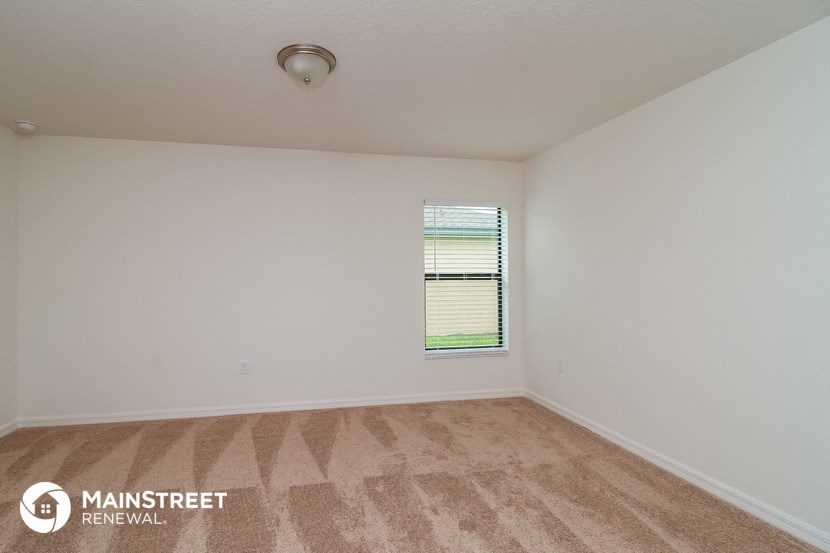 the spacious living room with carpeting and a window