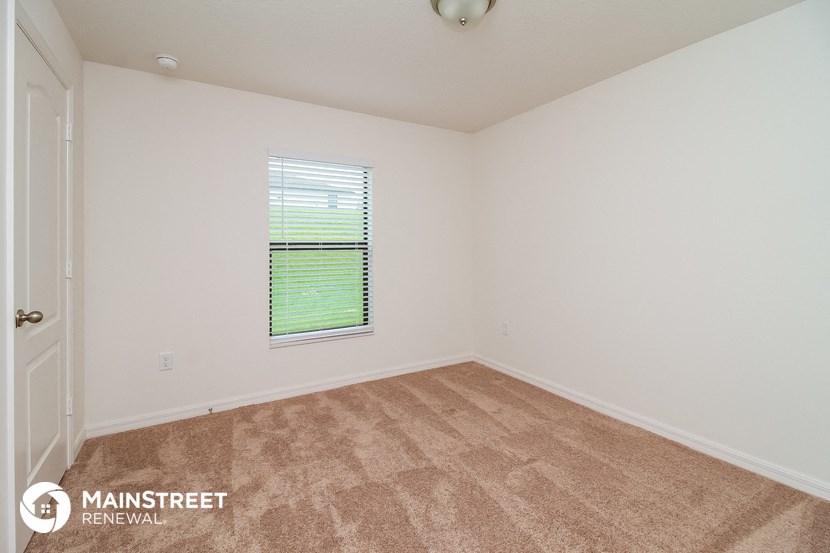 the spacious living room with carpeting and a window