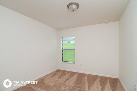the living room of an apartment with carpet and a window