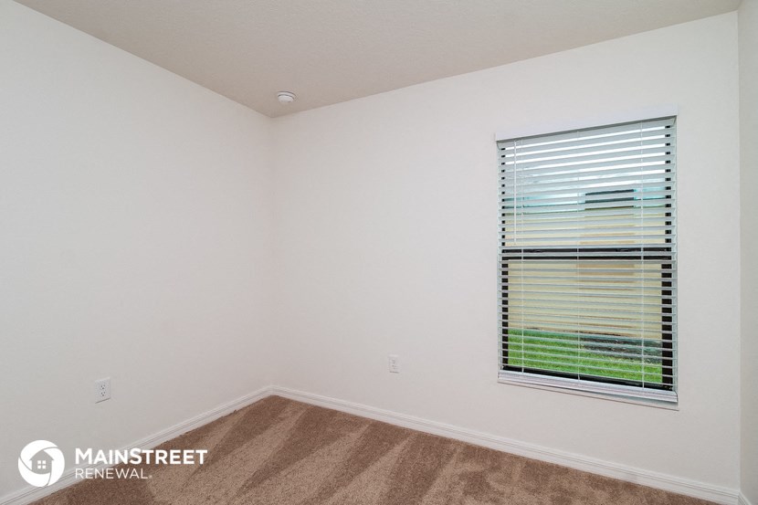 the upstairs bedroom with a large window and carpeted floor