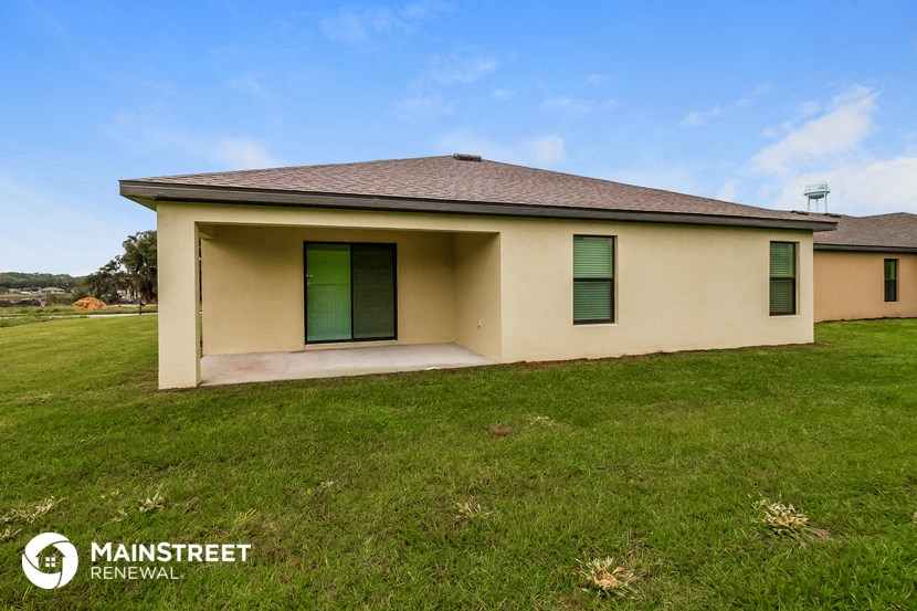 a small tan house with green shutters and a lawn