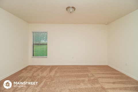 the spacious living room with carpet and window
