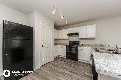 a kitchen with white cabinets and black appliances