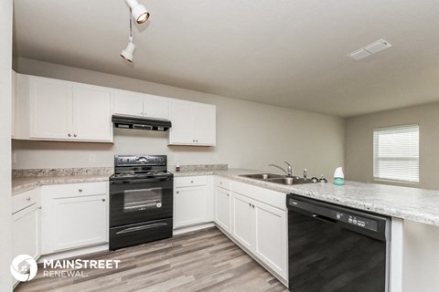 a kitchen with white cabinets and black appliances
