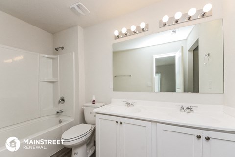 a white bathroom with a large mirror and a white toilet and sink