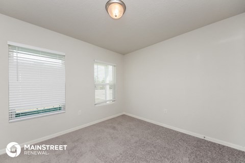 the spacious living room with two windows and carpeting