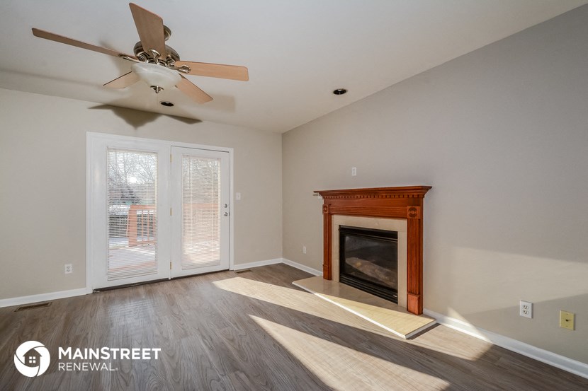 a living room with a fireplace and a ceiling fan