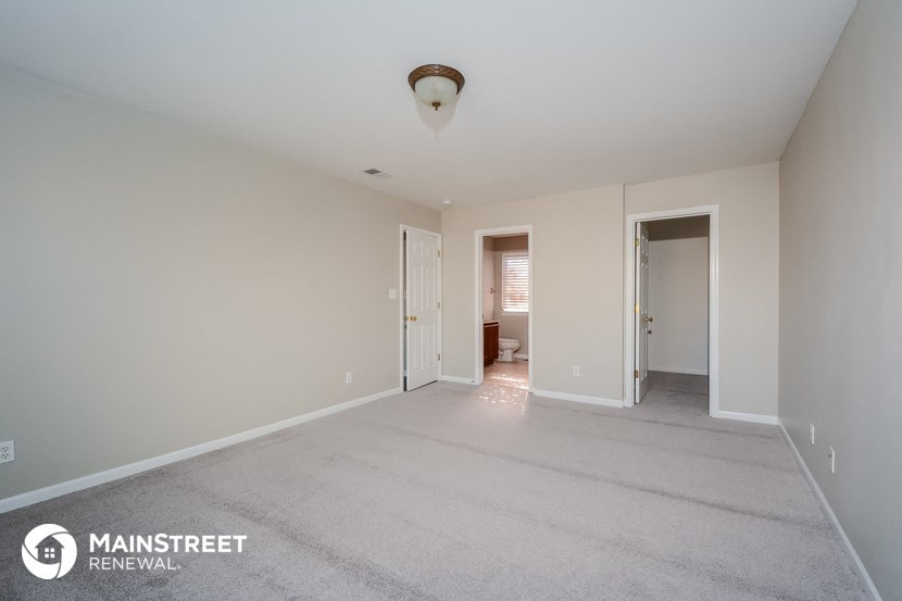 a master bedroom with a carpeted floor and a door to the bathroom