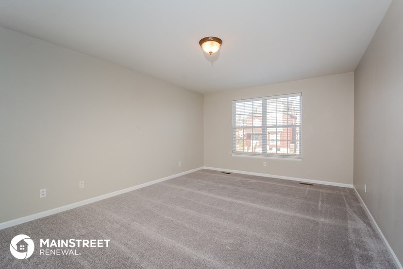 the spacious living room with carpeting and a window